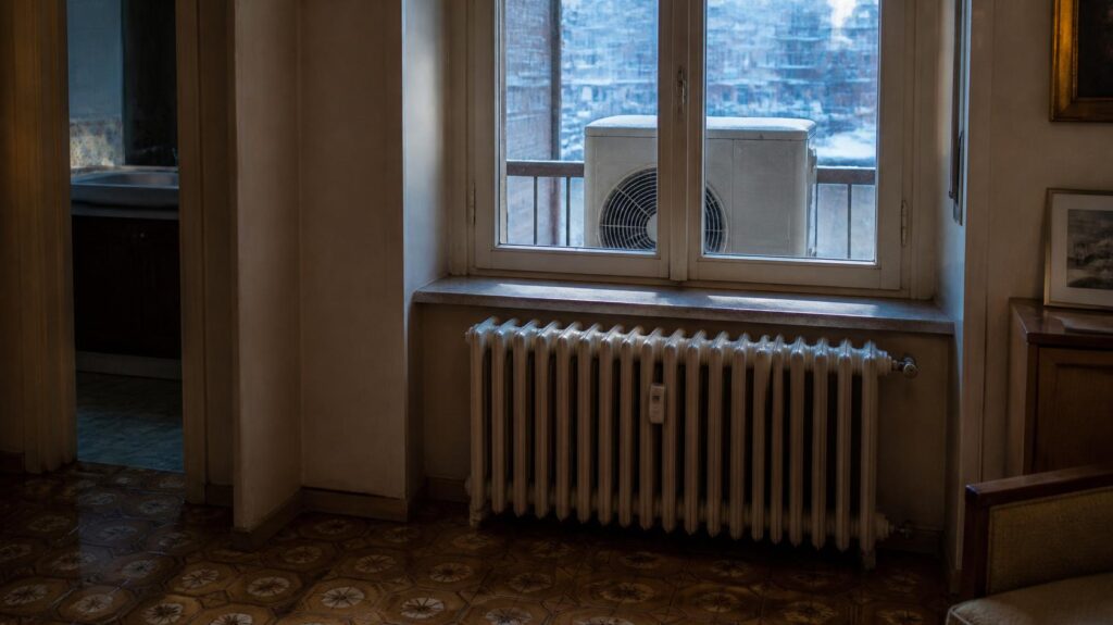 Vecchio termosifone in ghisa e unità esterna sul balcone: pompa di calore con i termosifoni da verificare prima dell'installazione