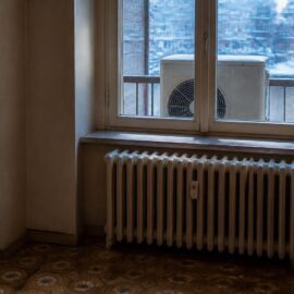 Vecchio termosifone in ghisa e unità esterna sul balcone: pompa di calore con i termosifoni da verificare prima dell'installazione